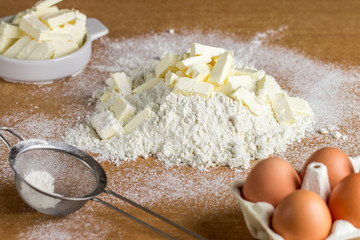Ingredients for prepare dough on a wooden table-wheat flour, butter or margarine, eggs, salt, sugar, milk. Selective focus