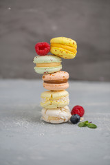 Colorfull different macaroons with berries on the grey background 