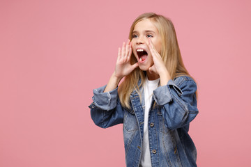 Little kid girl 12-13 years old in denim jacket isolated on pastel pink background in studio. Childhood lifestyle concept. Mock up copy space. Looking aside, screaming with hands gesture near mouth.