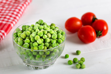 Frozen green peas in bowl on wooden background. Selective focus.