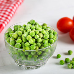 Frozen green peas in bowl on wooden background. Selective focus.