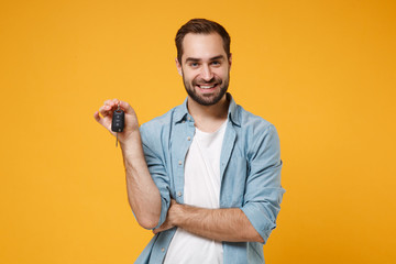Smiling handsome young man in casual blue shirt posing isolated on yellow orange wall background,...