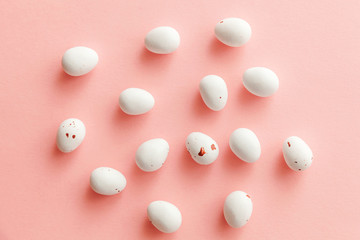 Happy Easter concept. Easter candy chocolate eggs and jellybean sweets isolated on trendy pastel pink background. Simple minimalism flat lay top view copy space