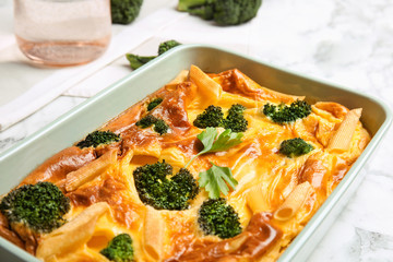 Tasty broccoli casserole in baking dish on white marble table, closeup