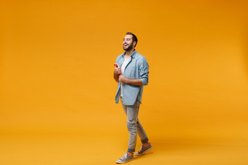 Cheerful young student man in casual blue shirt posing isolated on yellow orange wall background...