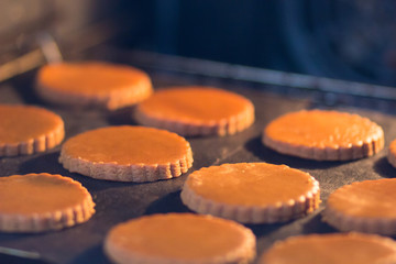 Round formed raw gingerbread dough on teflon baking sheet before to make cookies in the oven during...
