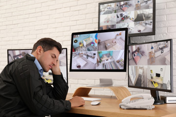 Fototapeta na wymiar Male security guard sleeping near monitors at workplace