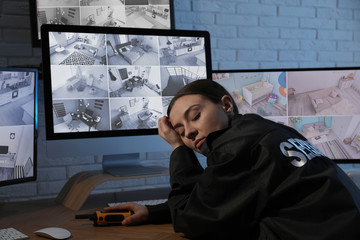 Female security guard sleeping near monitors at workplace