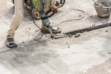 Construction worker using jackhammer drilling concrete surface