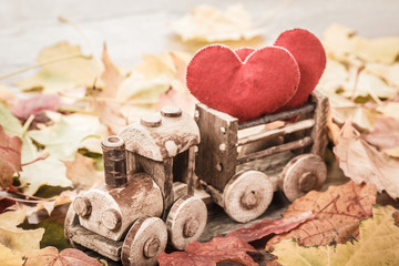 Toy train with hearts on autumn foliage. Concept of love of St. Valentine's Day greeting card.