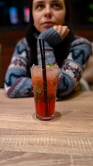 A woman drinks an alcoholic cocktail in a cafe. Close-up of a woman drinking a red cocktail in a cafe. Drinks, people and lifestyle concept-close