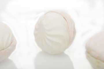 White-pink marshmallow with strawberry flavor on a white plate with reflection.