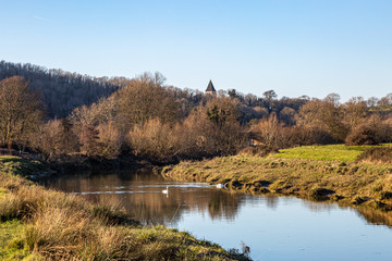 A scenic Sussex view along the River Ouse in Sussex, with the spire of Hamsey church visible behind bare trees
