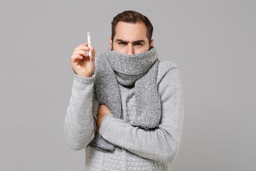 Young man in gray sweater isolated on grey background studio portrait. Healthy lifestyle ill sick...