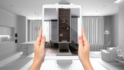Hands holding tablet showing modern living room, kitchen, total blank project background, augmented reality concept, application to simulate furniture and interior design products