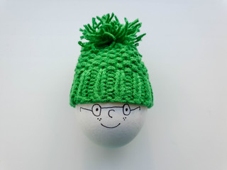 Egg in cute and lovely green knit warmer with bobble. Easter decoration idea. Decor for kids meals.