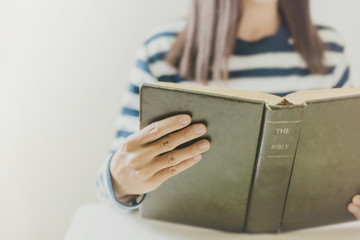 Woman holding the open bible in hands with copy space.