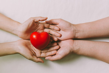 Hands couple holding red hearts, love, valentine, health care, donation and family insurance concepts, World Heart Day, prayer together.