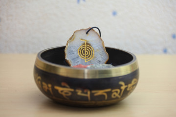 Agate crystal in the Tibetan singing bowl with the reiki symbol Cho Ku Rei. Meaning of the symbol:...