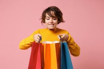 Pretty young brunette woman girl in yellow sweater posing isolated on pink wall background in...