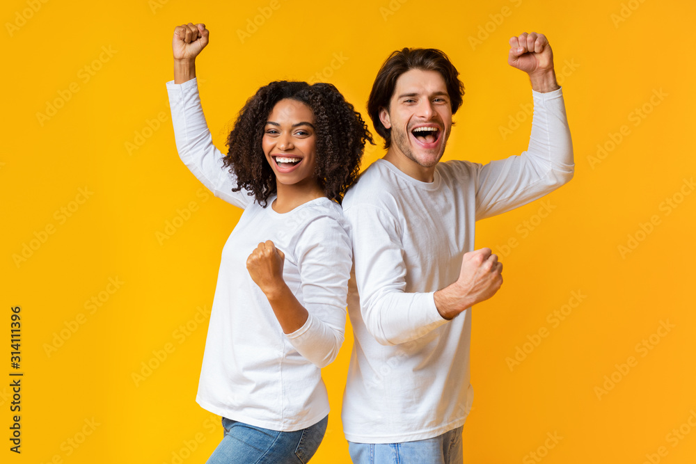 Wall mural joyful multiracial couple celebrating success, raising fists, rejoicing victory