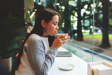 Portrait of a young girl she works as a freelancer in a cafe drinking a delicious hot Cup of coffee.