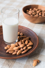 healthy food concept, almonds and glass of milk on a plate on the table