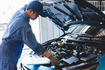 Car mechanic checking to maintenance vehicle by customer claim order in auto repair shop garage by...