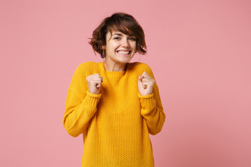 Smiling joyful young brunette woman girl in yellow sweater posing isolated on pastel pink...