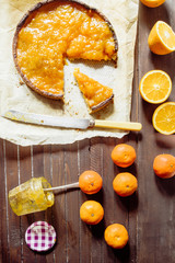 Tangerine citron tart on a rustic background with a vase of tangerine jam, top view, natural light