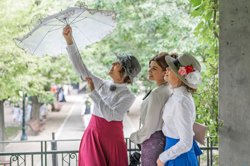 Obraz na płótnie Canvas three friends dressed in vintage clothes and umbrella laughing and having fun together