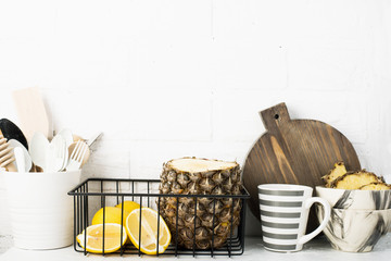Kitchen shelf lifestyle white background with fresh lemons, pineapple, kitchen tools, appliances, chopping boards, storage baskets. Eco-friendly life. Home style, minimalism, healthy eating.