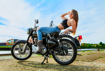 Fototapeta na wymiar An attractive girl on a motorbike posing outside