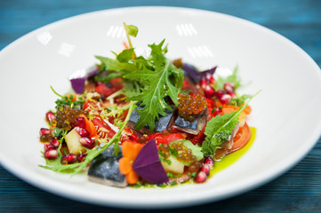 Escabeche fish dish with caviar: mackerel in marinade with vegetable, on a plate on the wooden blue background.