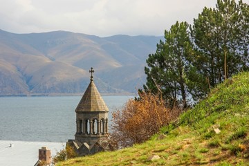Beautiful colorful landscape with a monastery, a lake Sevan and blurred mountains on cloudy day . Theological Seminary named after Vazgen I on lakeside Sevan. Armenia.