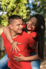 Obraz premium Hombre haciendo caballito a su novia en un parque publico