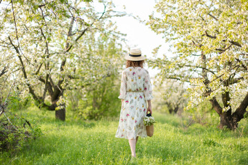 A gorgeous girl walks in a flowering spring garden. The concept of unity of man with nature