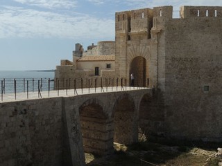 Fototapeta premium Siracusa Ortigia island – Maniace Castle sorrounded by the sea with stone walls and accessible by a stone bridge