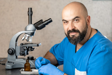 Male laboratory assistant examining biomaterial samples in a microscope.