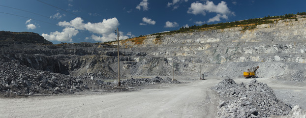 Relief of the quarry for limestone mining against the background of a blue sky with clouds, panorama. Mining industry.