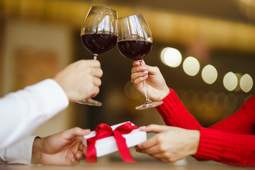 Couple clink glasses with red wine. Lovers give each other gifts.  Romance at restaurant for Valentine's Day concept. Relationship & Birthday concept.