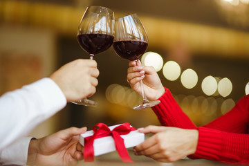 Couple clink glasses with red wine. Lovers give each other gifts.  Romance at restaurant for Valentine's Day concept. Relationship & Birthday concept.