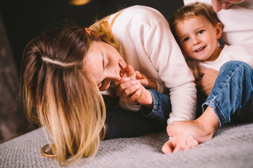 happy family is having fun in bedroom. Enjoying being together. Parents are tickling their little...