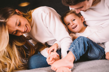 happy family is having fun in bedroom. Enjoying being together. Parents are tickling their little...