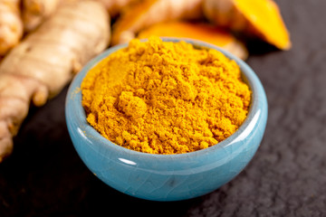 Food and drink, diet nutrition, health care concept. Raw organic orange turmeric root and powder, curcuma longa on a grunge cooking table. Indian oriental low cholesterol spices