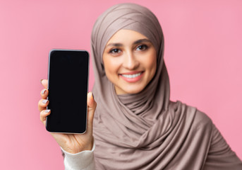 Modern smartphone with black screen in hands of smiling arabic woman
