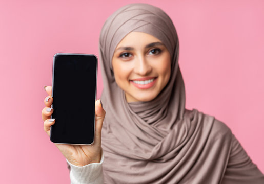 Modern smartphone with black screen in hands of smiling arabic woman - Powered by Adobe