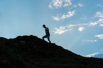 silhouette of a young man walking on a mountain