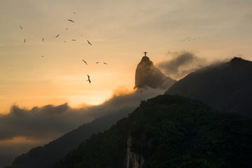 Sunset in Rio de Janeiro - Frigate Birds in sky with silhouette of Christ Redeemer rising from fog...