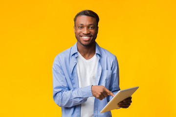Fototapeta na wymiar Smiling African American Guy Using Digital Tablet, Studio Shot